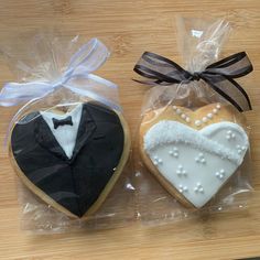 two decorated cookies in the shape of heart and tuxedo on a wooden table