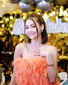 a woman in an orange feathered dress posing for the camera