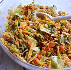 a salad in a glass bowl with a wooden spoon on the side, ready to be eaten