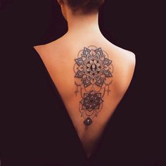 the back of a woman's neck with an intricate tattoo design on her left shoulder