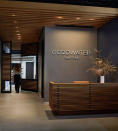 an entrance to a building with a plant in the center and a sign that says good water capital