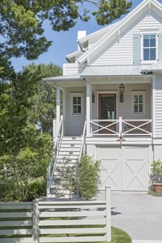 a white two story house with stairs leading up to the front door