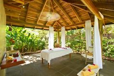 an outdoor spa with white sheets and towels on the bed, surrounded by greenery