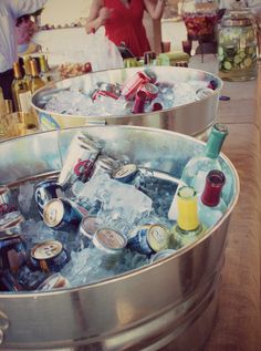 two large metal buckets filled with lots of bottles and cans sitting on top of a wooden table