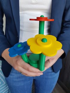 a woman is holding some plastic toys in her hands and wearing a blue blazer