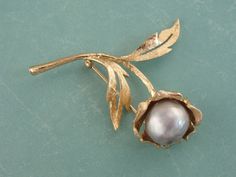 "Created in the era of the power suit, this brooch is the perfect bold statement for a lady's lapel! Brushed and etched gold forms a stylized blossom, set at the center with a large, beautiful cultured pearl of the finest quality! The color of the baroque shaped pearl is dove grey, pale and gleaming with overtones of purple and teal. Love this piece but want to make it more versatile, we here at Market Square Jewelers along with our master metalsmiths can convert this fantastic brooch into a nec Purple And Teal, Market Square, Floral Brooch, Power Suit, Dove Grey, Lovely Jewellery, Lily Of The Valley, Baroque Pearls, Eternity Bands