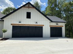 a white house with black garage doors and windows