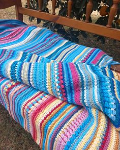 a crocheted blanket sitting on top of a wooden bench