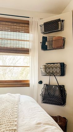 a bedroom with three baskets on the wall and two purses hanging from the hooks