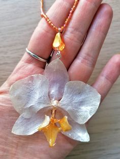 ☀️ Embrace the timeless beauty of orchids with this captivating handmade necklace! This exquisite necklace is more than just an accessory; it's a wearable work of art that captures the elegance and sophistication of orchids. Unlike traditional dried flowers, the orchid in this necklace is preserved in crystal-clear resin, ensuring its long-lasting beauty! Here's what makes this necklace special: Uniquely handcrafted: I cultivate and preserve the orchids myself, ensuring each necklace is a one-of-a-kind creation. You won't find another piece exactly like it! Timeless orchid design: The orchid's graceful silhouette and vibrant colors add a touch of sophistication and elegance to any outfit. Durable resin pendant: The crystal-clear resin encasing the orchid protects it from damage, ensuring y Unique Orchid-colored Jewelry Gift, Unique Orchid-colored Jewelry As A Gift, Unique Orchid Colored Jewelry For Gift, Unique Orchid Jewelry For Gift, Elegant White Necklace With Pressed Flowers, Orchid Flower Pendant Jewelry Gift, Orchid Flower Pendant Jewelry For Gift, Orchid Flower Necklace For Gift, Spiritual White Flower Necklaces