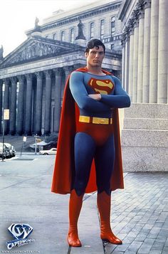 a man dressed as superman standing in front of a building