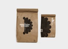 two brown bags sitting next to each other on top of a white surface with the packaging in front of them