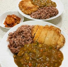 two white plates filled with different types of food on top of a table next to each other