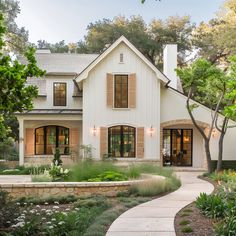 a large white house with lots of windows and plants around it's front entrance