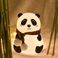 a panda bear night light sitting next to some bamboo stalks and lights in the snow