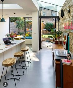 an open kitchen and dining area with wooden stools on the counter, along with a brick wall