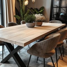 a wooden table surrounded by chairs and plants