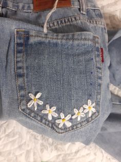 a pair of jeans with daisies embroidered on them