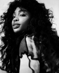 a black and white photo of a woman with long curly hair wearing a sheer top