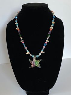 a necklace on a mannequin with beads and a bird