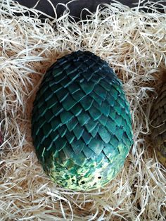 an egg is sitting in some straw on top of another eggs head and the shell has been painted green