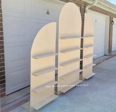 two white bookcases on the side of a building with garage doors in the background