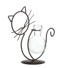 a glass vase with a cat's head sticking out of it, next to a wire sculpture