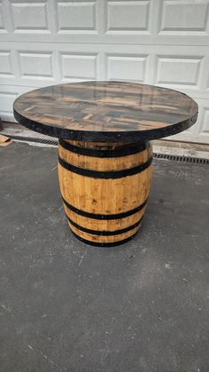 a wooden barrel table sitting in front of a garage door