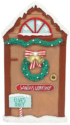 a santa's workshop door ornament with a wreath and bells on it