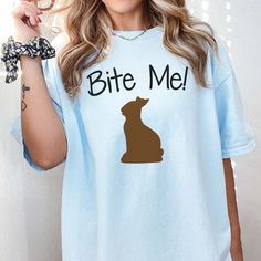 Embrace the festive spirit with the Bite Me Bunny Bella Tee, crafted to bring a smile and a dash of humor to your wardrobe. This charming t-shirt flaunts a unique design that subtly weaves in a playful twist, making it an ideal choice for those who love a good laugh. Infuse your style with personality and wit, showcasing a piece that's as distinctive as you are. Perfect for individuals who enjoy a lighthearted approach to fashion, this tee is your go-to for fun and casual outings. Playful Design Novelty Crew Neck Top With Screen Print, Playful Crew Neck Top With Funny Text, Novelty Blue Tops With Funny Print, Novelty Tops With Funny Print And Crew Neck, Novelty Tops With Funny Print And Relaxed Fit, Novelty Crew Neck Top With Funny Text, Gift Card Games, Bite Me, Family Mom