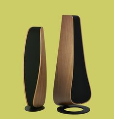 two wooden vases sitting next to each other on a green background, one is black and the other is brown