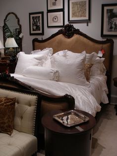 a bed with white linens and pillows in a bedroom next to pictures on the wall