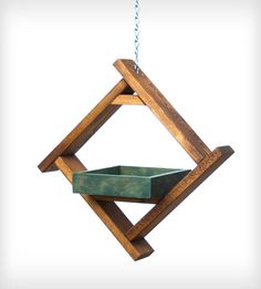 a wooden bird feeder hanging from a chain on a white background in the shape of a triangle