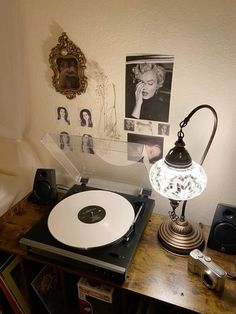 a record player sitting on top of a wooden table next to a wall with pictures