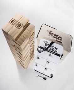 a stack of wooden blocks sitting next to a bag and some pens on a white surface