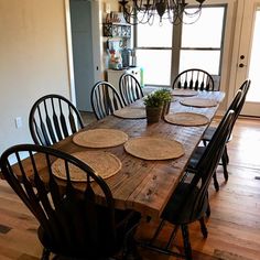 a dining room table with place mats on it and chairs around it, in front of a doorway