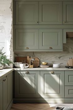 an image of a kitchen setting with green cabinets and marble counter tops in the sunlight