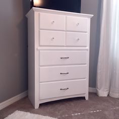 a white dresser sitting in a bedroom next to a window