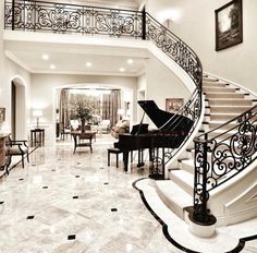 a grand piano sitting in the middle of a living room next to a stair case