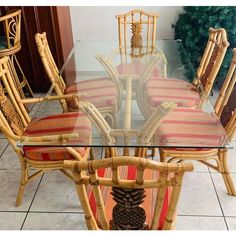 a dining room table with chairs made out of bamboo and red striped upholstered cushions