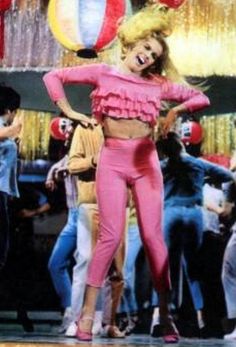 a woman standing in front of a group of people wearing pink outfits and clown masks