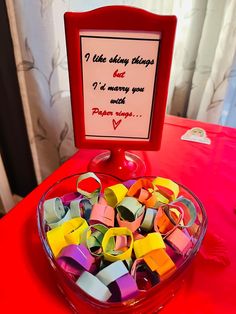 a bowl filled with lots of different colored paper clips on top of a red table