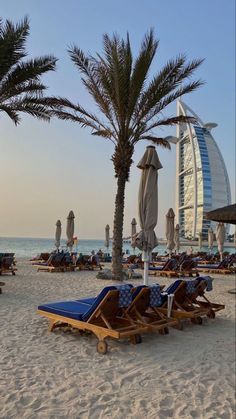 lounge chairs and umbrellas on the beach with burj al arab hotel in the background