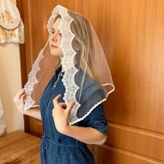 a woman wearing a veil and dress standing in front of a dresser