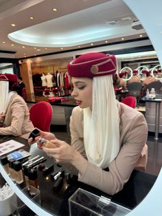 a woman in a red hat is looking at her cell phone while sitting at a counter