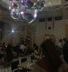 a room filled with people sitting at tables and balloons floating in the air above them