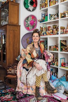 a woman sitting on top of a chair in front of a book shelf filled with books