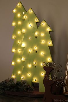 a lighted christmas tree sitting on top of a wooden table next to a framed photo