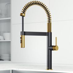 a kitchen faucet with gold spouting on the side and black handles