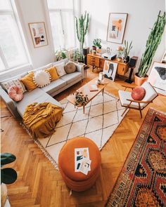 a living room filled with lots of furniture and plants on top of the wooden floor